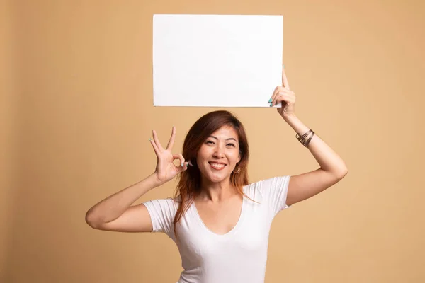 Young Asian woman show OK with  white blank sign. Royalty Free Stock Photos