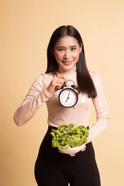 Saat ve salata ile genç Asyalı kadın.