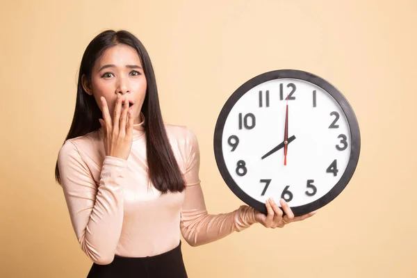 Sleepy jonge Aziatische vrouw met een klok in de ochtend. — Stockfoto