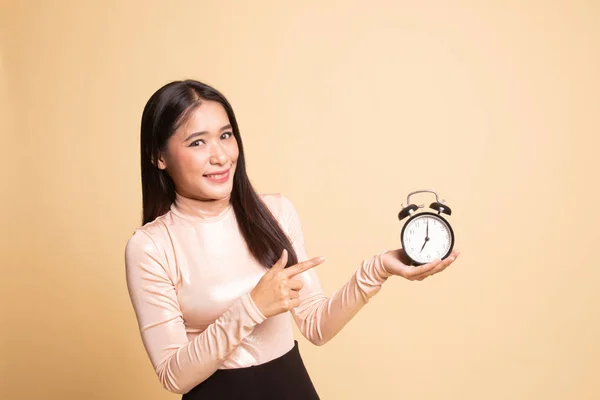 Young Asian woman point to a clock.