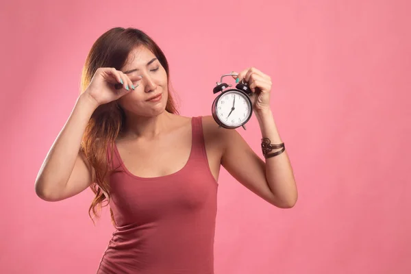 Sleepy young Asian woman with a clock in the morning. — Stock Photo, Image