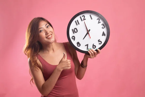 Young Asian woman thumbs up with a clock.