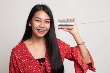 Teneke kutu telefon ile genç Asyalı kadın.