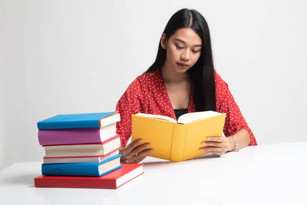 Ung asiatisk kvinna läsa en bok med böcker på bord. — Stockfoto