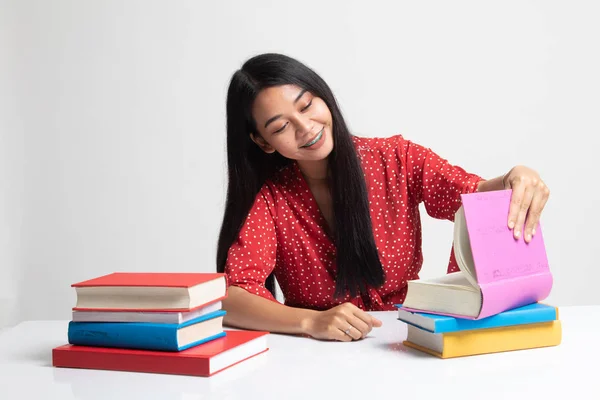 Ung asiatisk kvinna läsa en bok med böcker på bord. — Stockfoto