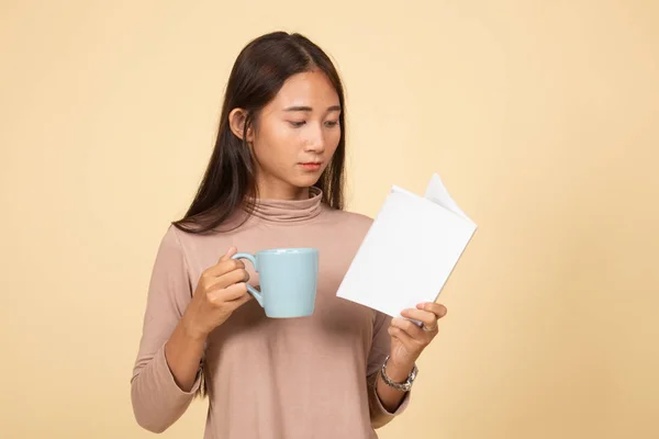 Giovane donna asiatica con un libro e una tazza di caffè . — Foto Stock