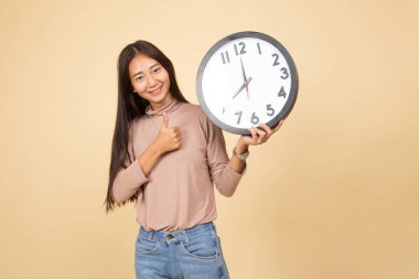 Genç Asyalı kadın başparmak yukarıya ile bir masa saati.