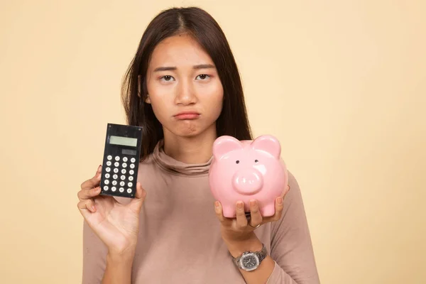 Nešťastný Asijské žena s Kalkulačka a prasátko. — Stock fotografie