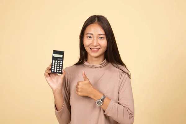 Asian woman thumbs up with calculator.