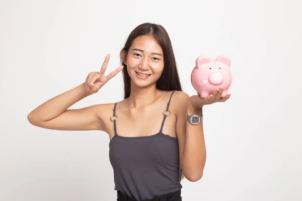 Asiatico donna spettacolo vittoria segno con maiale moneta banca . — Foto Stock