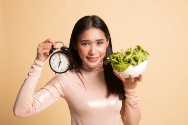Saat ve salata ile genç Asyalı kadın.