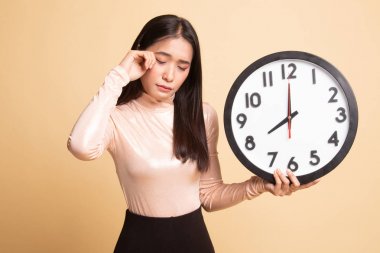 Sabah bir saat ile uykulu genç Asyalı kadın.