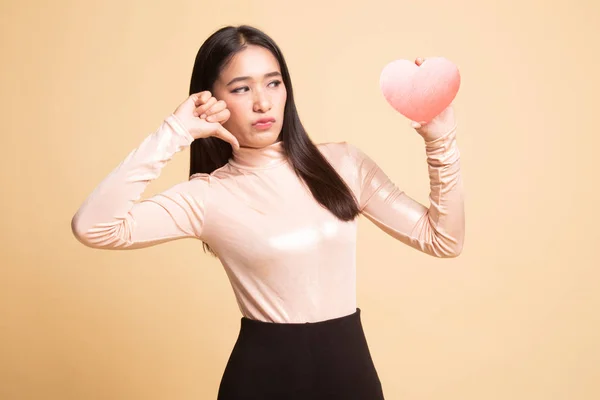 Asian woman thumbs down with red heart.