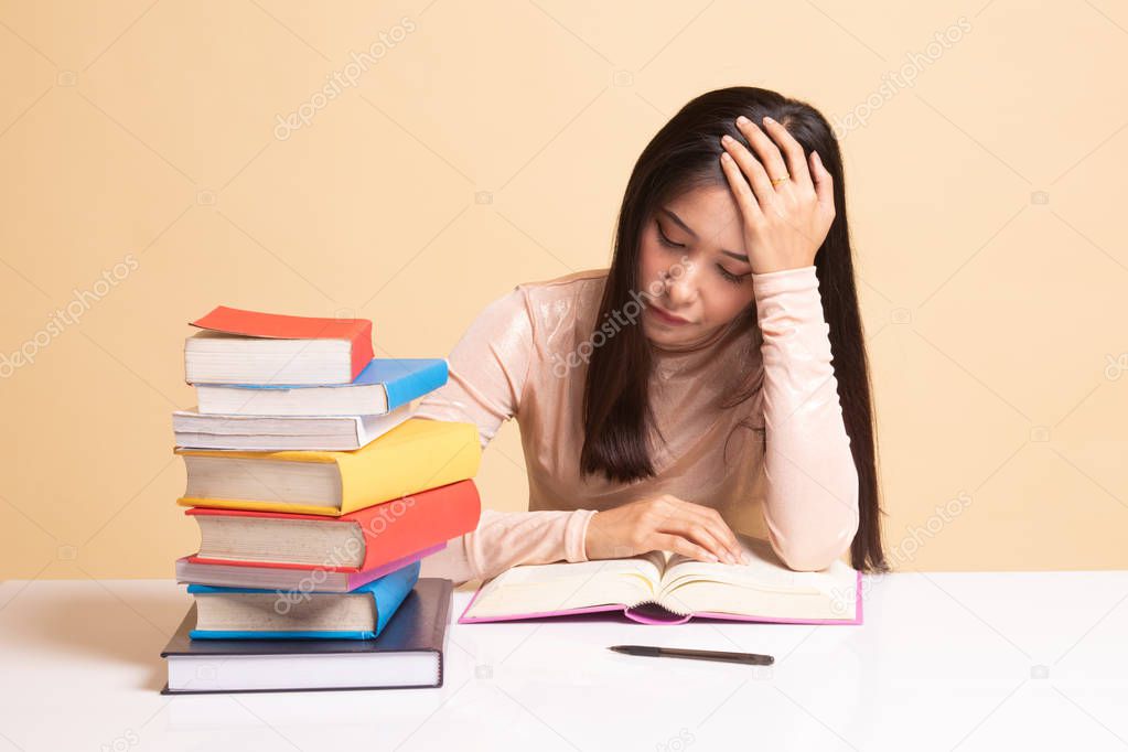 Exhausted Young Asian woman read a book with books on table.