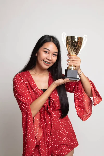 Successful young asian woman holding a trophy.