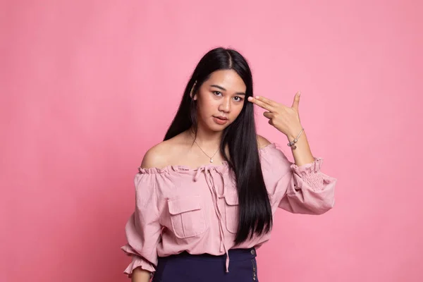 Beautiful young Asian woman holding fingers in gun gesture.