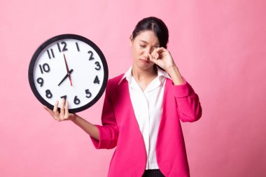 Sabah bir saat ile uykulu genç Asyalı kadın.