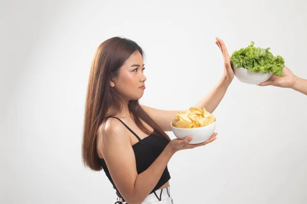 Jeune femme asiatique avec des chips de pommes de terre disent non à la salade . — Photo