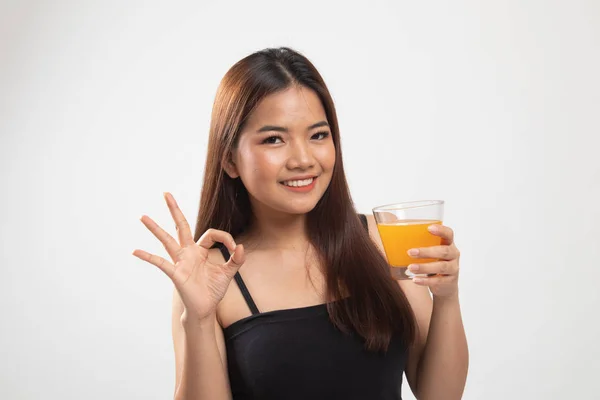Jovem mulher asiática beber suco de laranja mostrar sinal OK . — Fotografia de Stock
