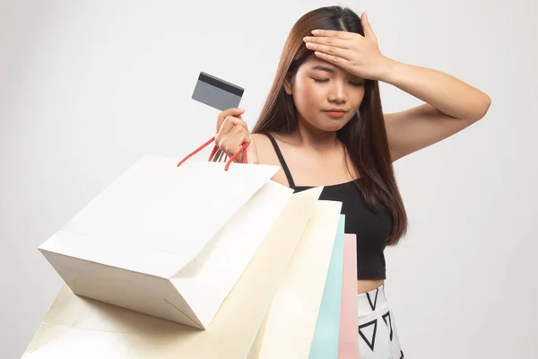 Ongelukkige jonge Aziatische vrouw met shopping tassen en credit card. — Stockfoto