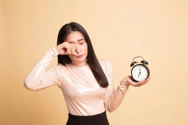 Sleepy jonge Aziatische vrouw met een klok in de ochtend. — Stockfoto