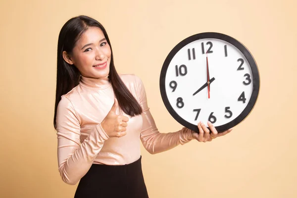 Young Asian woman thumbs up with a clock. — Stock Photo, Image