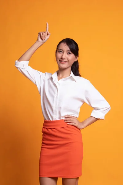 Junge asiatische Frau lächelt und zeigt nach oben. — Stockfoto