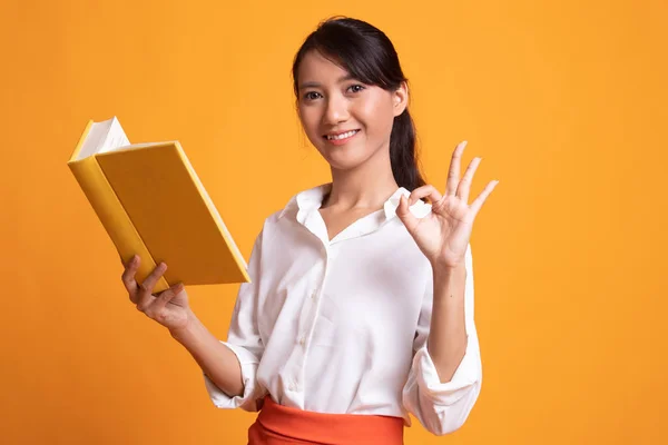 Junge asiatische Frau zeigen ok mit ein Buch. — Stockfoto