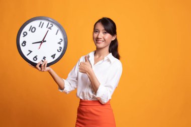 Genç Asyalı kadın başparmak yukarıya ile bir masa saati.