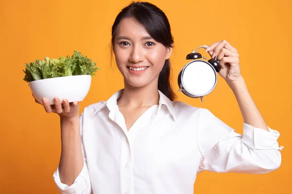 Ung asiatisk kvinna med klocka och sallad. — Stockfoto