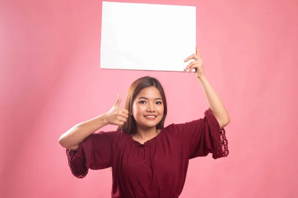 Молодая азиатка показывает большие пальцы с белым пустым знаком . — стоковое фото