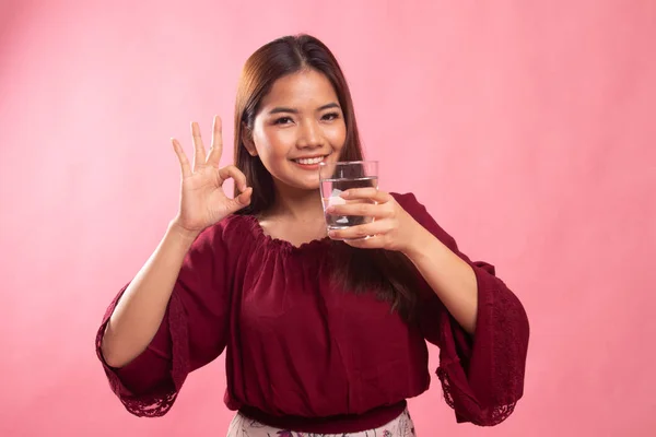 Ung asiatisk kvinna Visa Ok med ett glas vatten. — Stockfoto