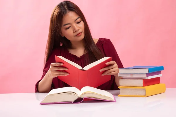 Junge Asiatin liest ein Buch mit Büchern auf dem Tisch. — Stockfoto