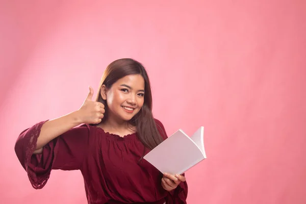 Joven mujer asiática pulgares arriba con un libro . — Foto de Stock