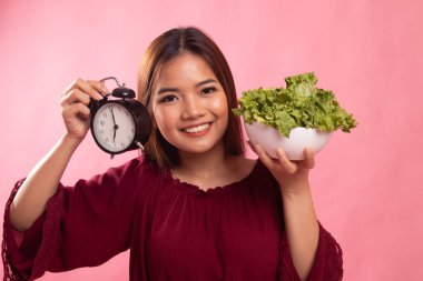 Saat ve salata ile genç Asyalı kadın.