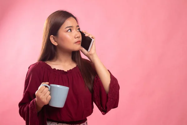 Mladá asijská žena s mobilním telefonem a šálek kávy. — Stock fotografie