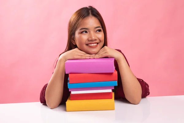 Feliz joven asiática mujer leer un libro con libros en la mesa . — Foto de Stock