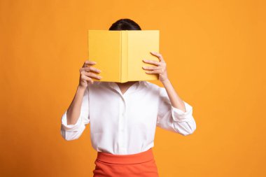 Young Asian woman with a book cover her face.