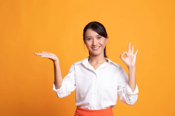 Schön junge asiatische Frau zeigen Handfläche Hand und ok Zeichen. — Stockfoto