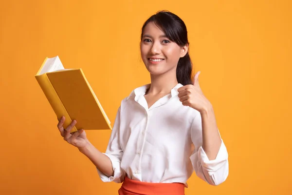 Jovem mulher asiática polegares para cima com um livro . — Fotografia de Stock