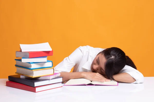 Erschöpfte junge Asiatin schläft mit Büchern auf dem Tisch. — Stockfoto