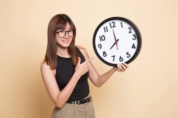 Young Asian woman point to a clock.