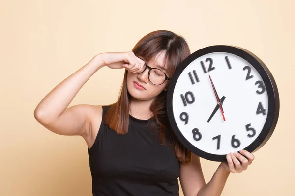 Sleepy jonge Aziatische vrouw met een klok in de ochtend. — Stockfoto