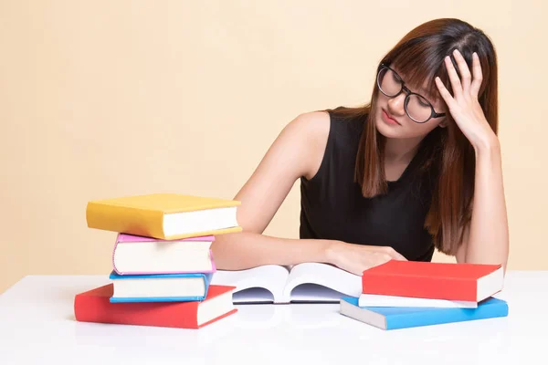 Esausta giovane donna asiatica leggere un libro con libri sul tavolo . — Foto Stock