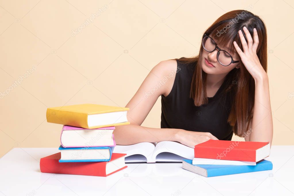 Exhausted Young Asian woman read a book with books on table.