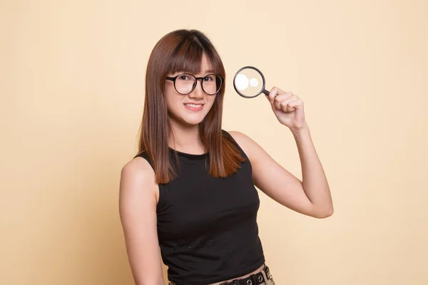 Young Asian woman with a magnifying glass. — Stock Photo, Image