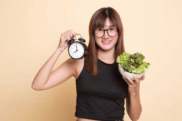 Young Asian woman with clock and salad.