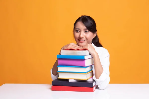 Glad ung asiatisk kvinna läsa en bok med böcker på bord. — Stockfoto