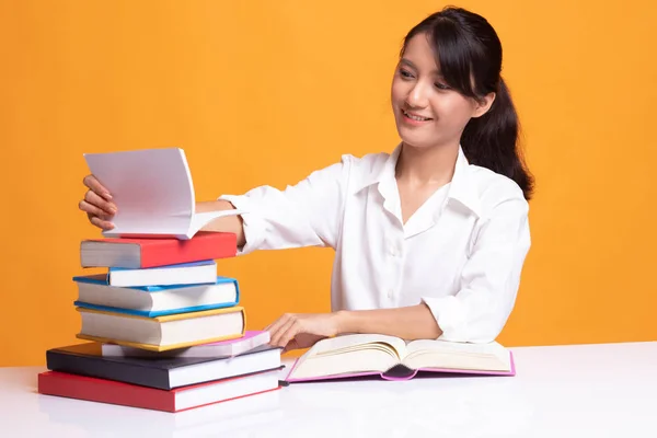 Joven mujer asiática leer un libro con libros en la mesa . — Foto de Stock