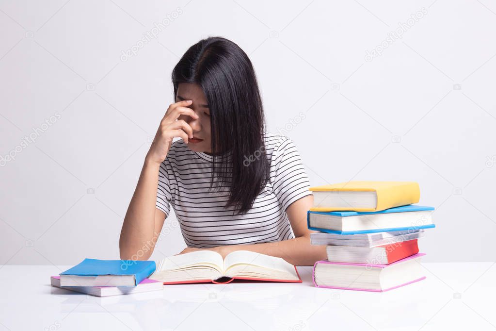 Exhausted Asian woman got headache read a book with books on tab